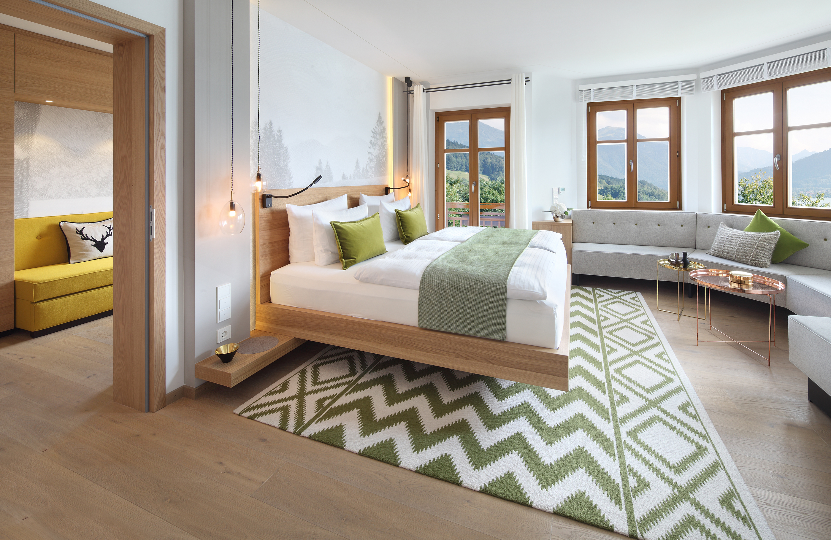 Ein helles in grün Tönen gehaltenes Schlafzimmer mit vielen Fenstern und einer großen Sitzbank
