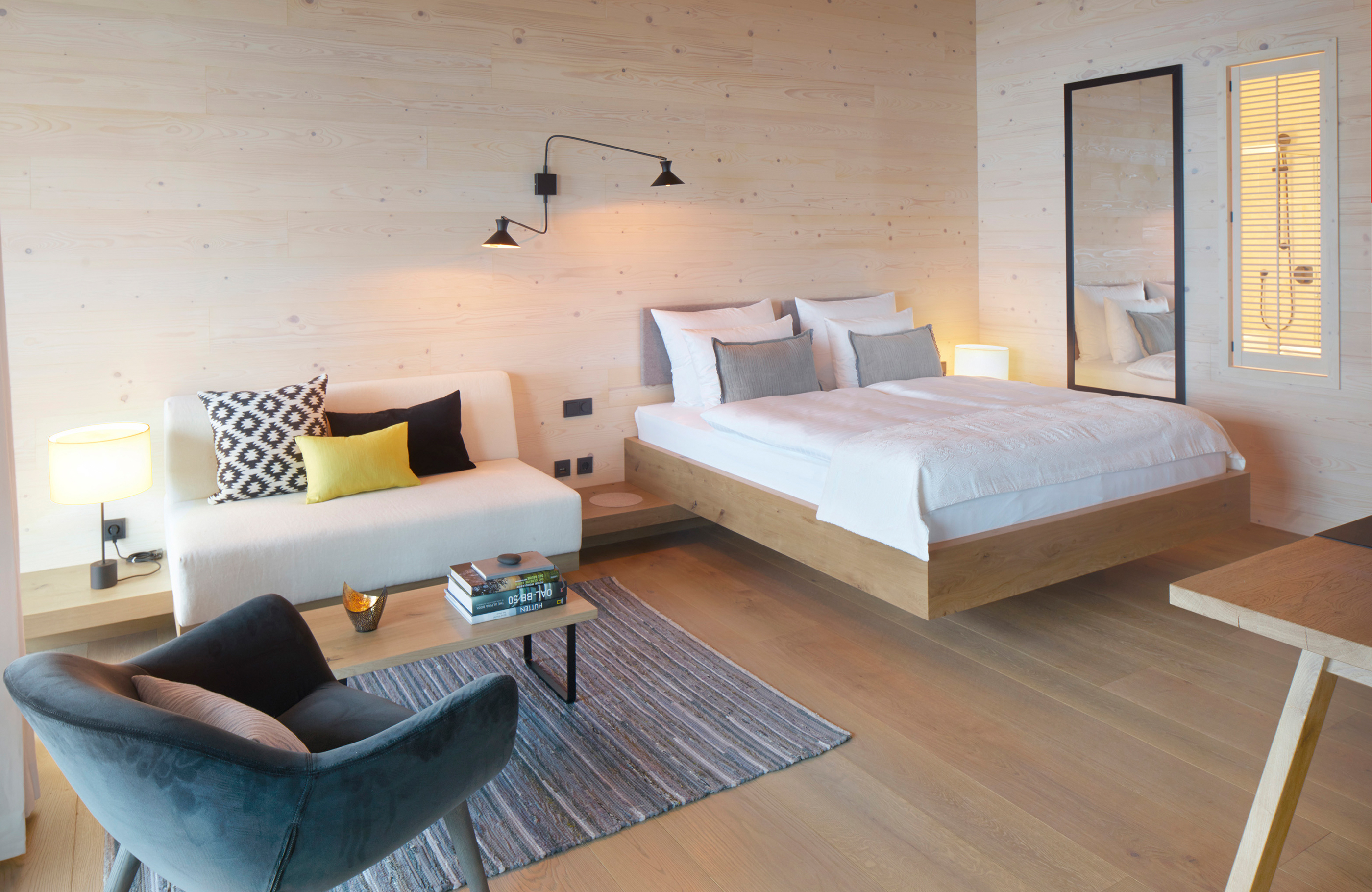 Aufnahme von einem Bett, einer Couch und einem dunkelblauen Sessel im Alpenchalet