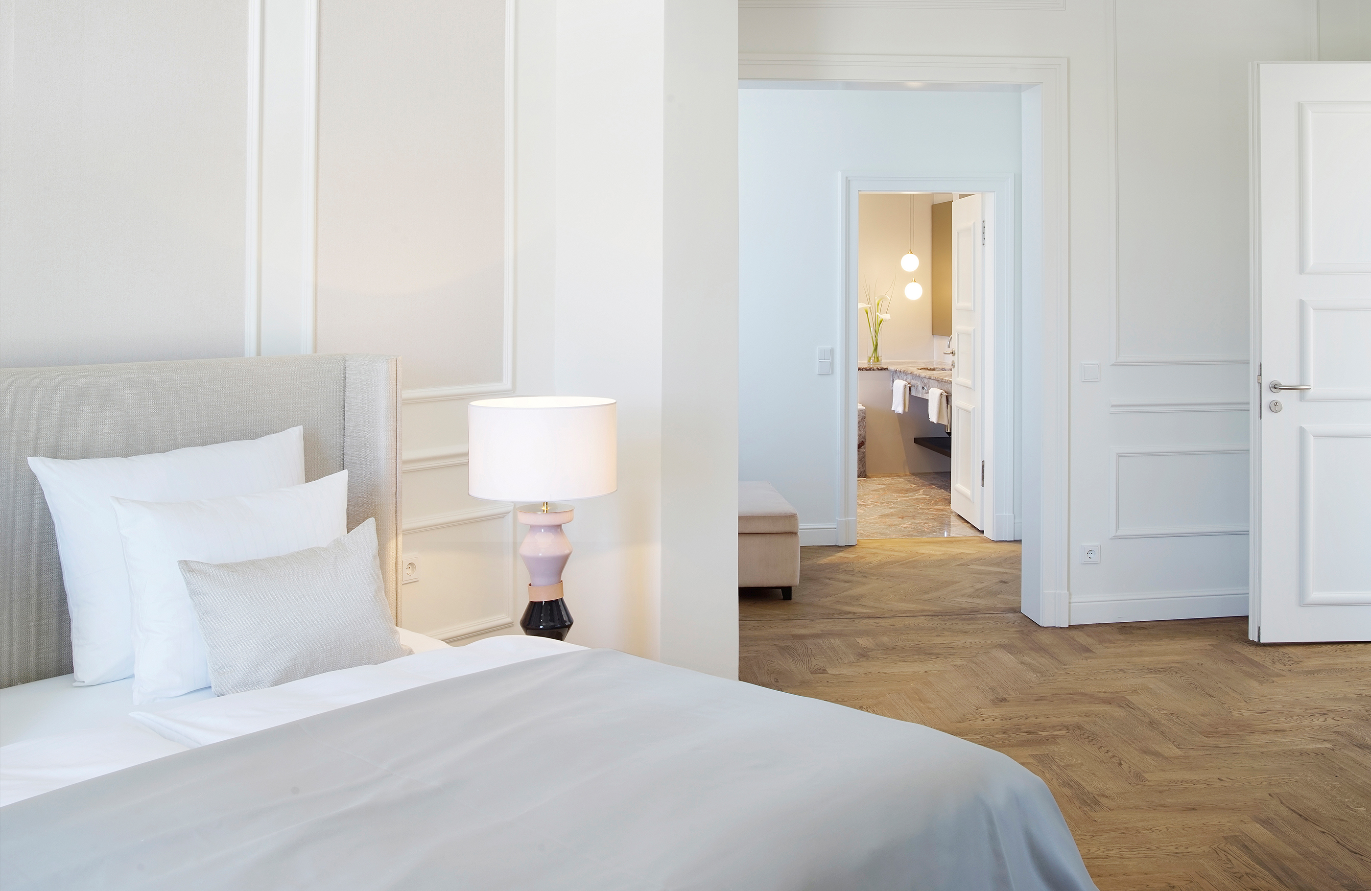 Blick über das gemütliche Bett auf den Flur und das angrenzende Badezimmer einer Deluxe Suite
