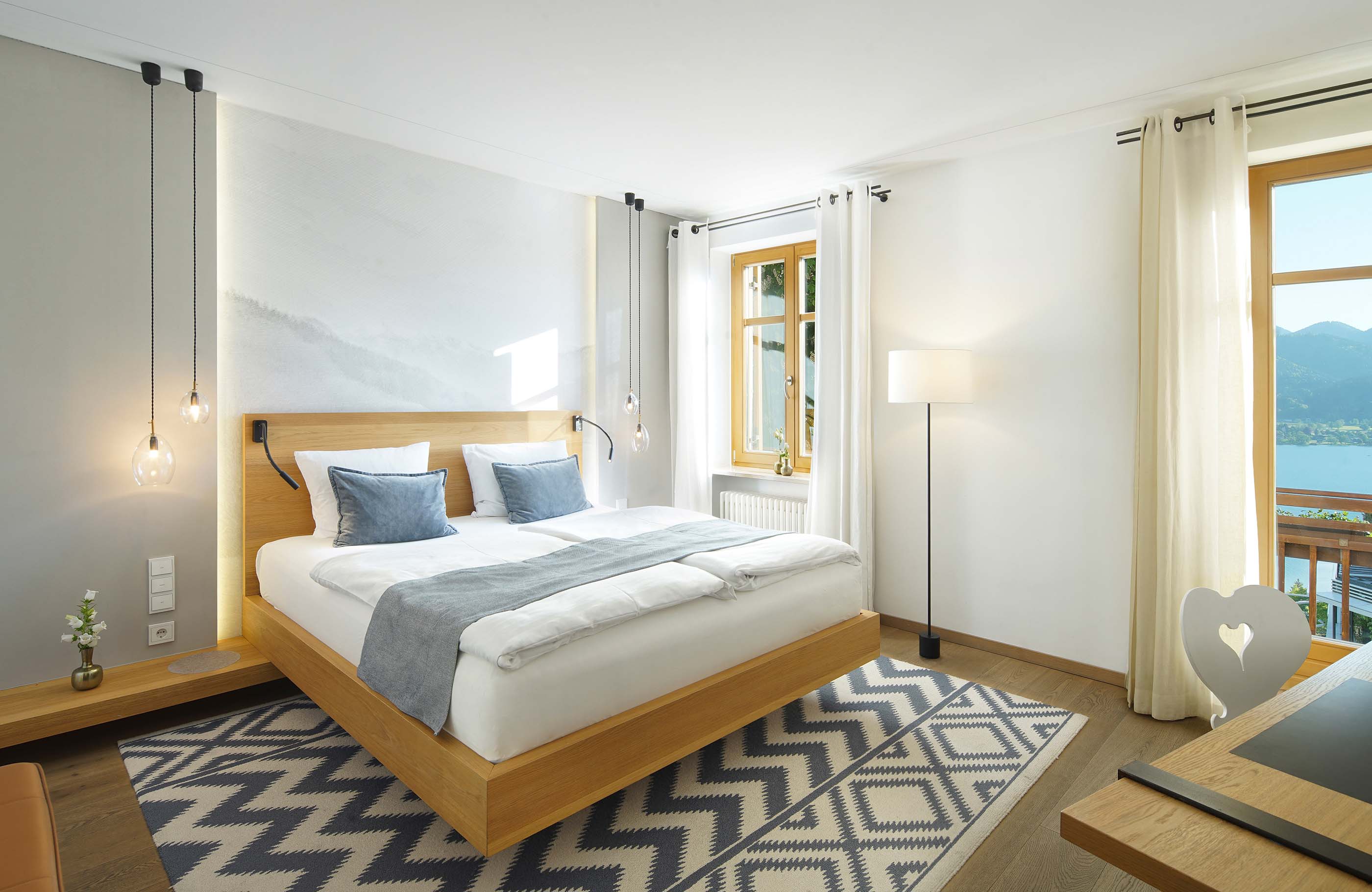 Blick ins Schlafzimmer mit gemustertem Teppich und hellen Fenstern 