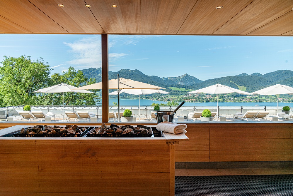 Ausblick aus dem Fenster der Panoramasauna Day Spa am Tegernsee mit Blick auf die Liegestühle am Seeufer
