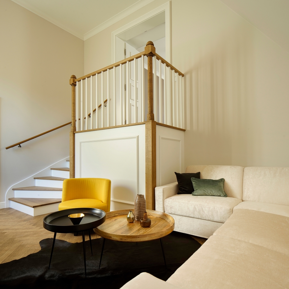 Blick vom beigen Sofa in den Raum auf eine kleine Treppe